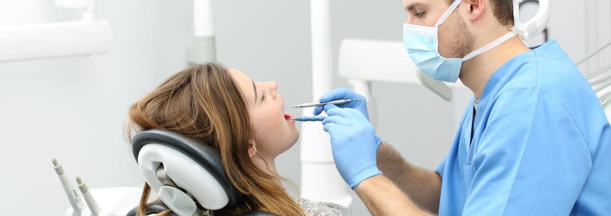 Dr. med. dent. - Zahnarzt, der gerade eine Patientin behandelt