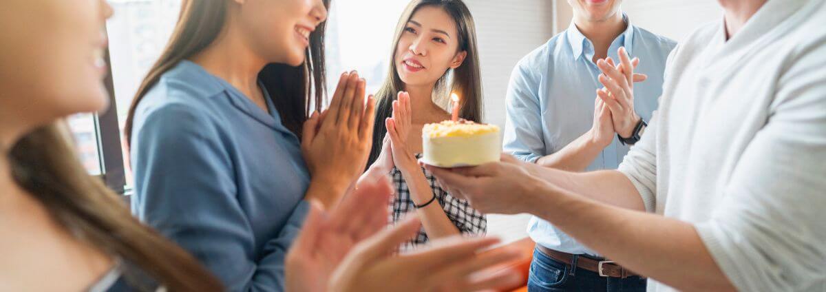 Frau, die zum Geburtstag mit einem Kuchen überrascht wird.