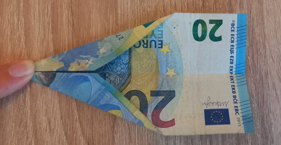 Gefalteter 20 Euro Schein, der mit dem Finger festgehalten wird.