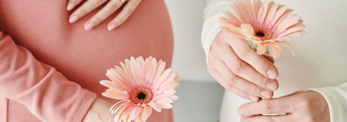 Schwangere Frauen mit einer Blume in der Hand.