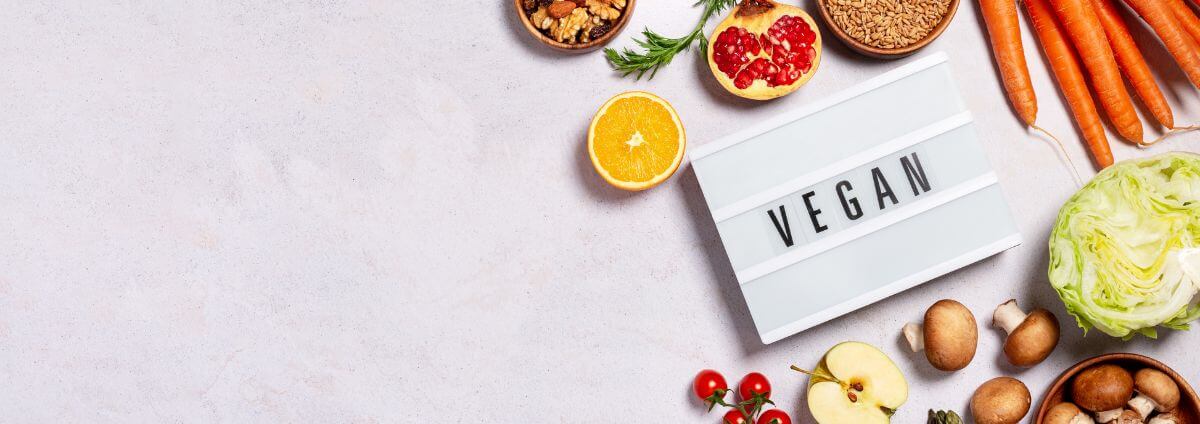 Obst, Gemüse und ein Schild auf dem "vegan" steht.