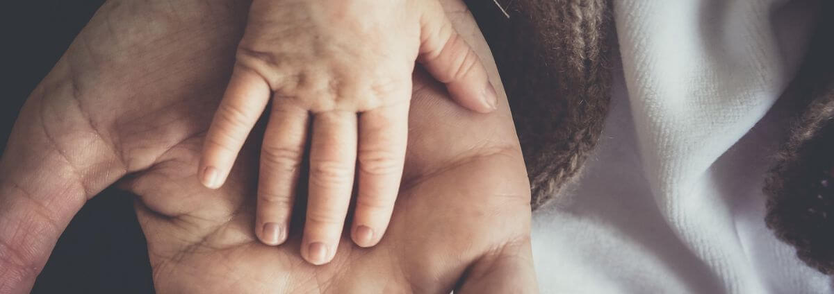 Hand eines Babys auf der Hand vom Papa.