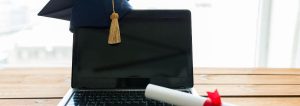 Doktorhut und Urkunde auf einem Laptop. Sinnbild für Geschenke zum Master.