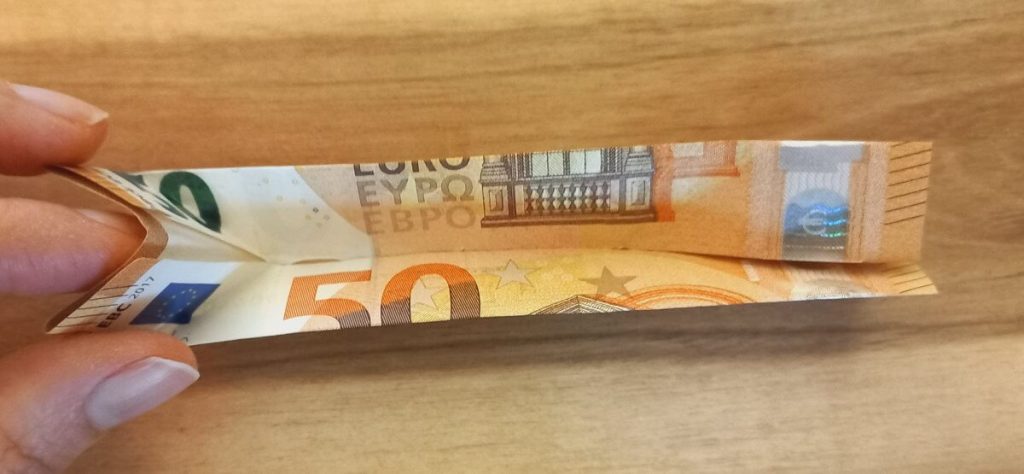Geldschein, der mit den Fingern nach innen gefaltet wird.
