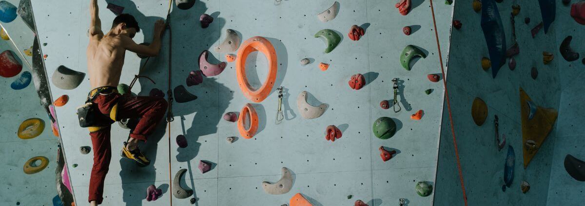 Mann, der in einer Boulderhalle klettert.