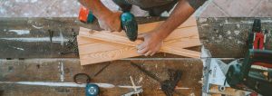 Handwerker, der ein Loch in ein Holzbrett bohrt.